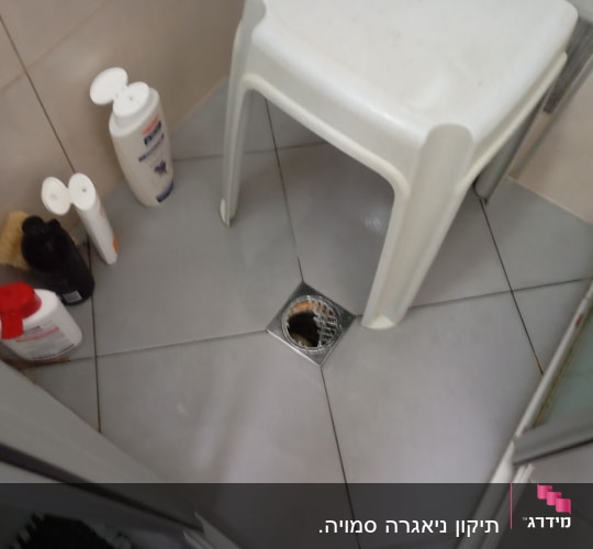 ניקוז רצפה במקלחת עם כיסא פלסטיק